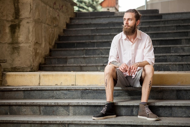 Tattoed and bearded guy posing outdoor in the city