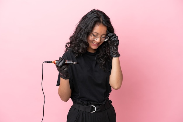 Tattoo artist asian woman isolated on pink background laughing