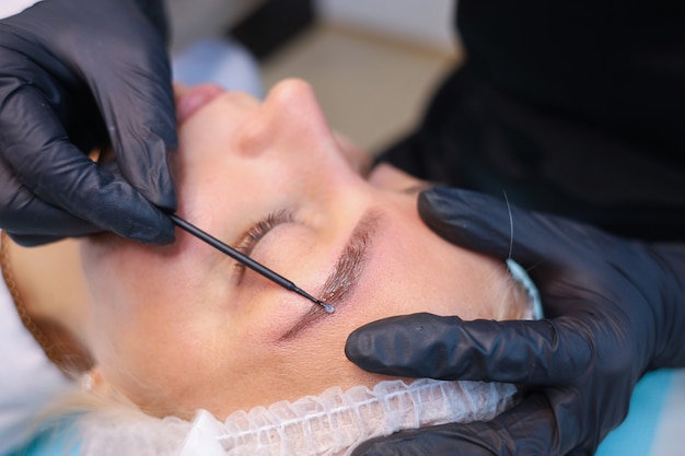 Tattoo Artist combs client's eyebrow with microbrash