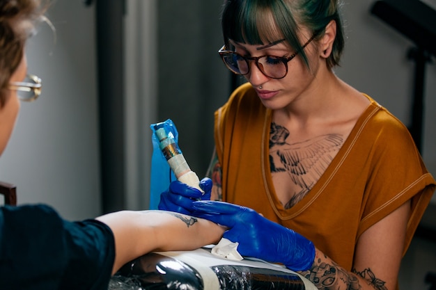 Photo tattoo artist creating a tattoo on a girl's arm.