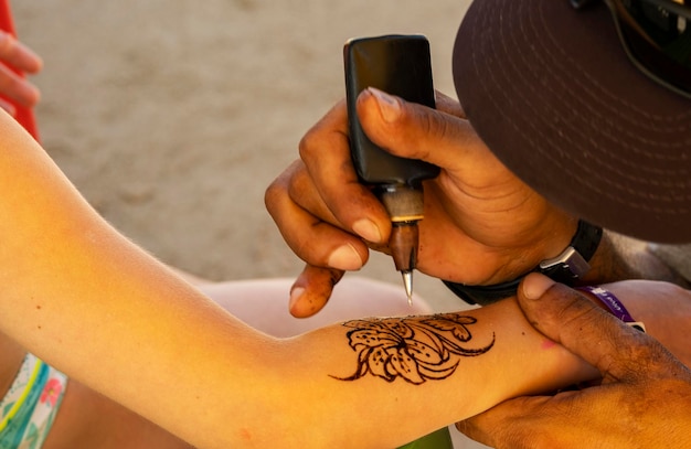 Tattoo artist doing henna tattoo on a little girl's arm