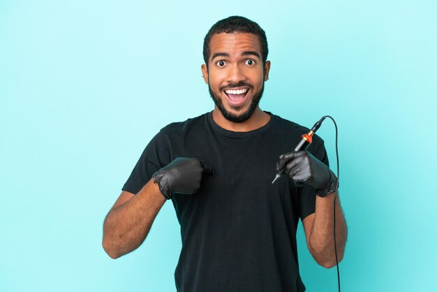 Tattoo artist Ecuadorian man isolated on blue background with surprise facial expression