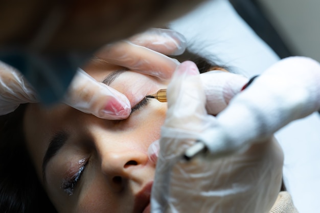 Tattoo artist performs permanent makeup of eyelashes