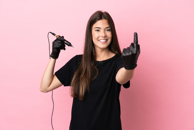 Tattoo artist woman isolated on pink background doing coming gesture