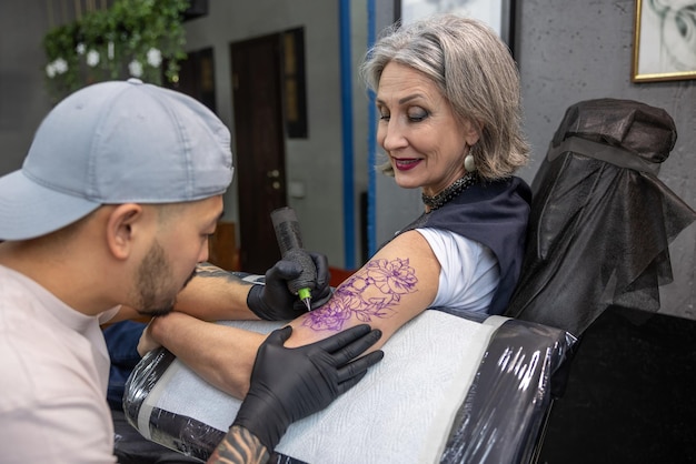 Tattoo master drawing tattoo on womans arm