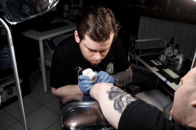 Tattoo master at work makes drawing on hand