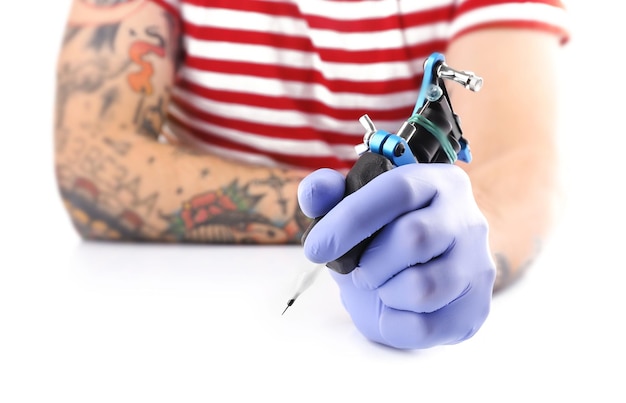 Photo tattoo master working in blue medical gloves with tattoo machine close up