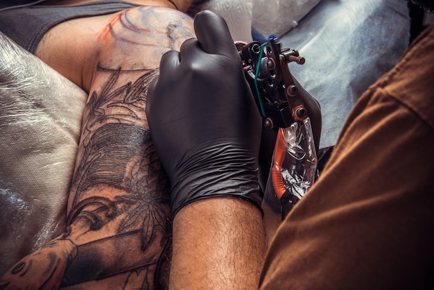 Tattoo specialist create tattoo in tattoo parlor./Professional tattooist posing in tattoo studio.