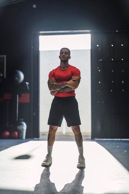 tattooed young guy in a gym door with powerful pose