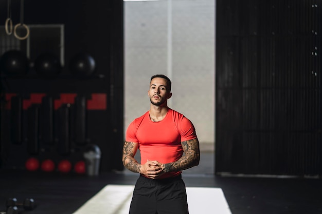 tattooed young guy in a gym door with powerful pose