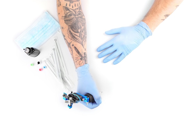 Photo tattooist hands in blue gloves with special equipment isolated on white background close up