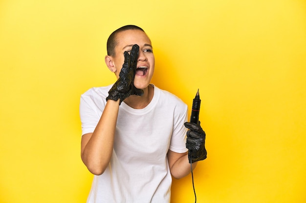 Tattooist woman in studio shaved head yellow background shouting and holding palm near opened mouth