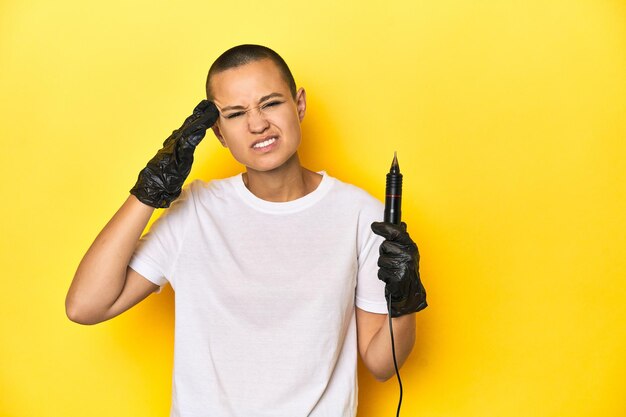 Tattooist woman in studio shaved head yellow background showing a disappointment gesture