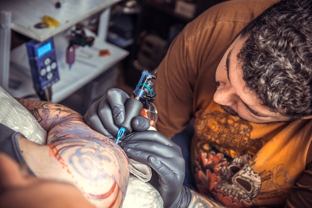 Tattooist working tattooing in tattoo studio.