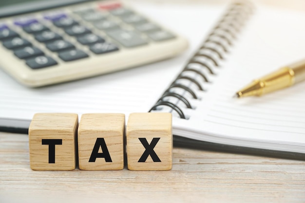 Tax concept with wooden blocks desk background with calculator notebook pen on business