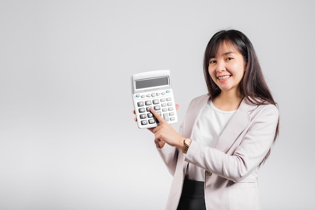 Tax day concept. Woman confident smiling holding calculator and finger point device, Portrait excited happy Asian female studio shot isolated on white background, Account and finance counting income