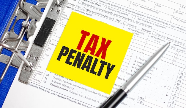 Tax penalty word on yellow sticker with tax form and pen