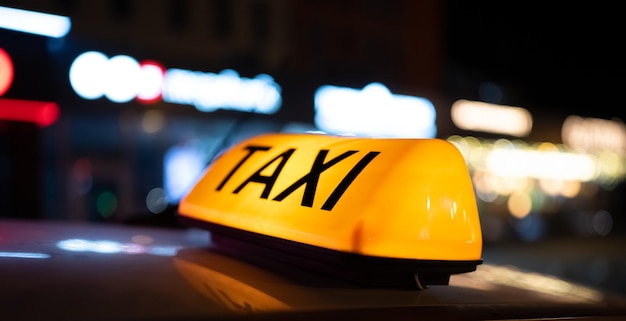 Taxi car light on dark street at night cab sign on the vehicle roof glowing in the dusk