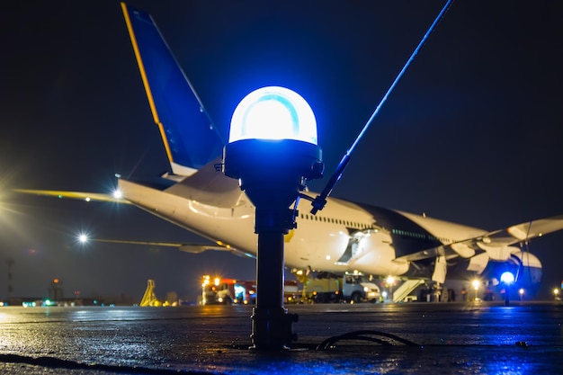 Taxiway, side row lights on the background of a large passenger aircraft at the night airport apron