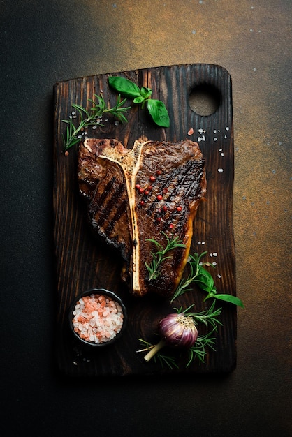 Photo the tbone or porterhouse steak of beef cut from the short loin on a dark slate background