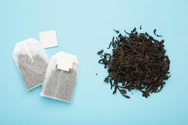 Tea bag and with dry tea leaves on blue background