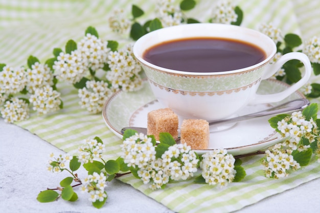 Tea in a beautiful white cup. Breakfast. A branch of flowering spirea. Japanese concept wabi sabi