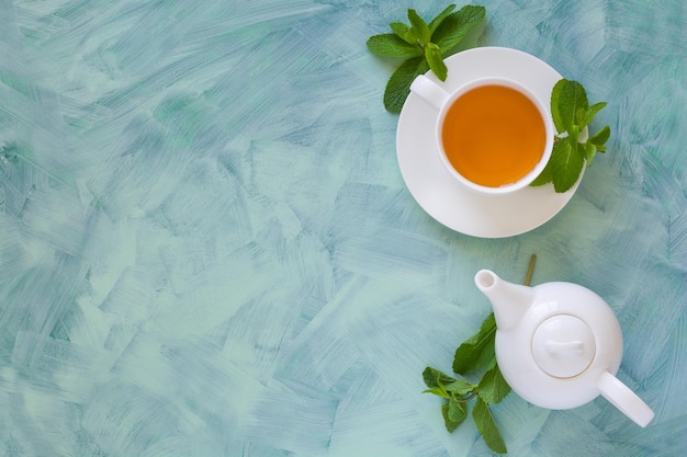 Tea concept Teapot and cup with green herbal tea decorated mint leaves on wooden background