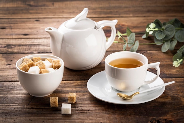 Tea concept, white cup of tea and teapot, sugar in white bowl