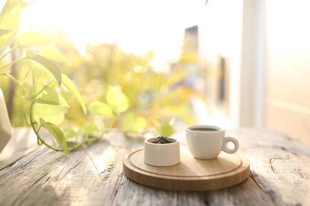 Tea cup and tea pot and green leaves on wooden table