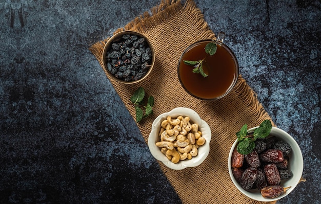 Tea cup with dried dates fruit and apricot on dark background