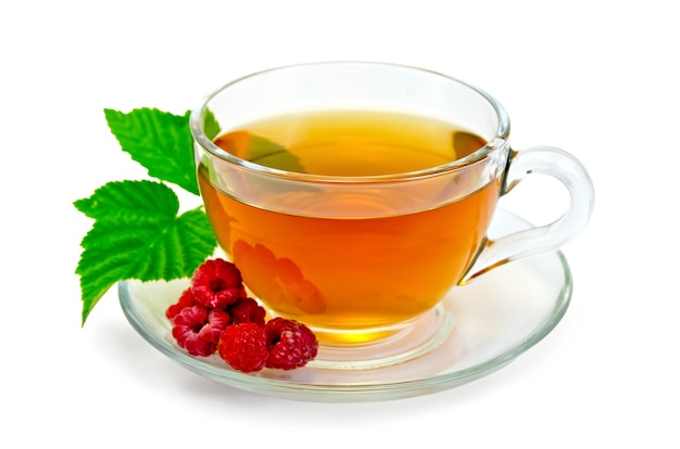 Tea in a glass cup, berries and green leaf raspberry isolated on a white background