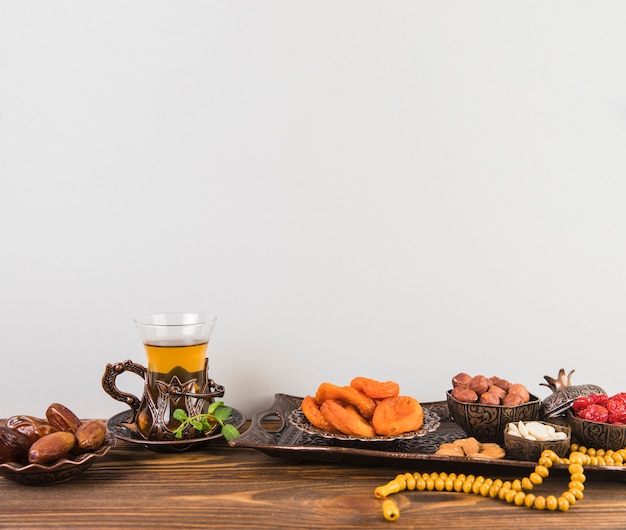 Tea glass with dried fruits and beads on table