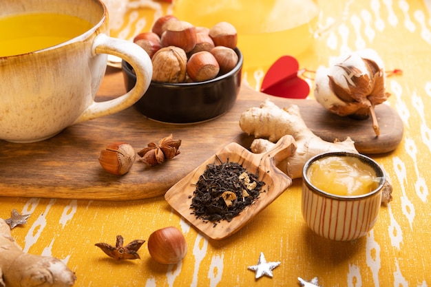 Tea ingredients on table dry tea in wooden spoon, ginger root and honey.