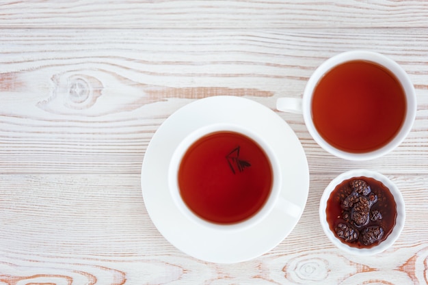 Tea and jam of berries on a light wooden table