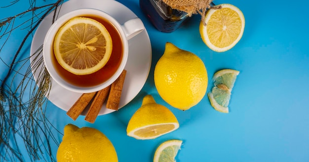 Tea and lemon in a white cup over blue background copyspace concept