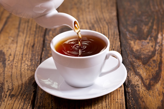 Tea pouring into white cup from teapot