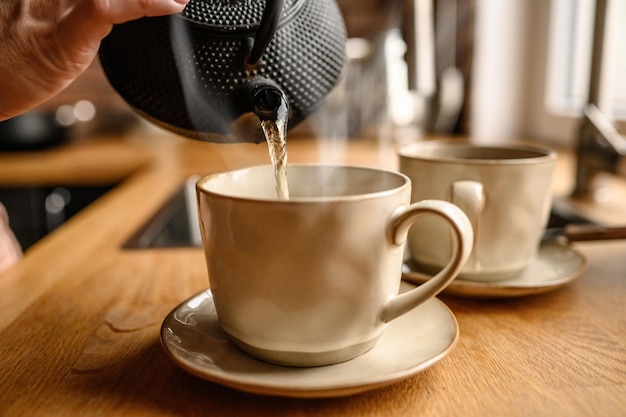 Tea preparation with teapot and cups at kitchen