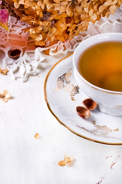 Tea in the rustic vintage Chic style. Garden tea Party. Teapot of dry flowers. Cup of tea with autumn decor on table, with hydrangea and pumpkin