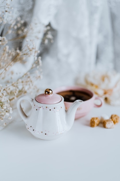 Tea set, teapot with sugar cubes and a cup with brewed tea  