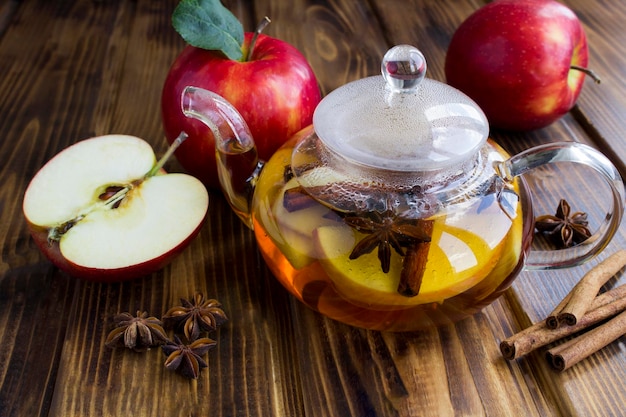 Tea with apple cinnamon and anise in the glass teapot on the wooden background Closeup