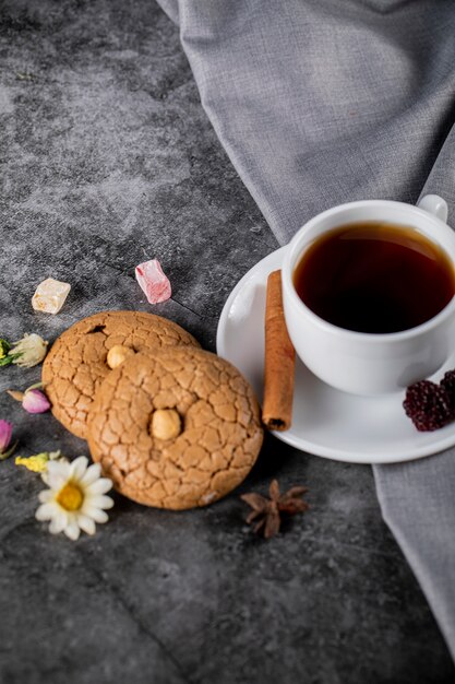 Tea with berries, cinnamon and cookies on a blue marble