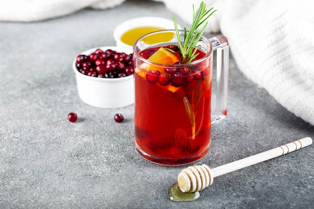 Tea with cranberries, cinnamon , orange, rosemary and honey in a glass cup