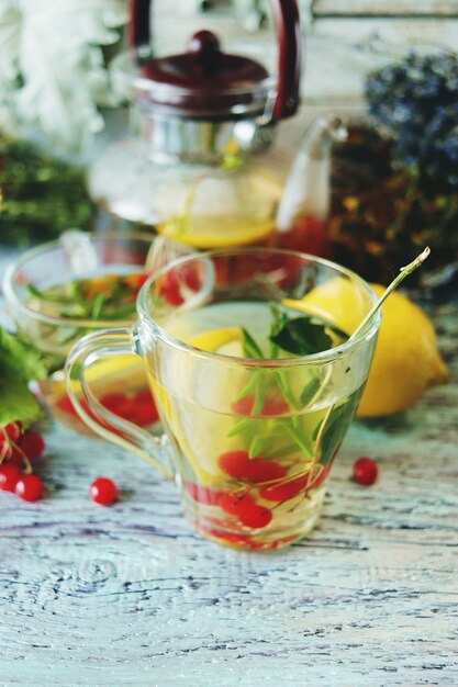 Tea with healthy herbs flowers berries and lemon in a glass cup on a wooden background