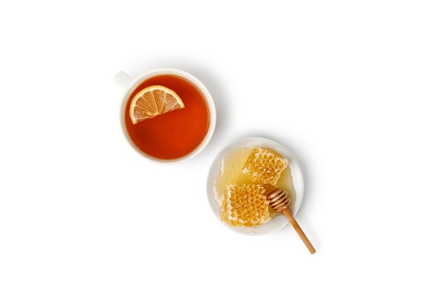 Tea with lemon honey in Honeycomb on a plate with honey dipper isolated on white background Top view