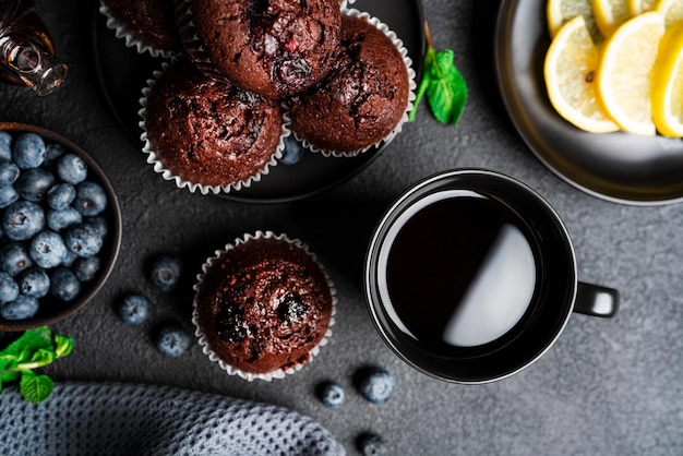 Photo tea with muffins on a dark background chocolate muffins with blueberries