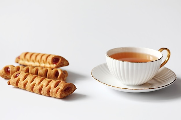 Tea with pastries for breakfast. Sweets and pastries with nuts for tea on white background. A coffee cup and patties.