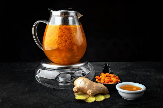 Tea with sea buckthorn and ginger in a glass teapot