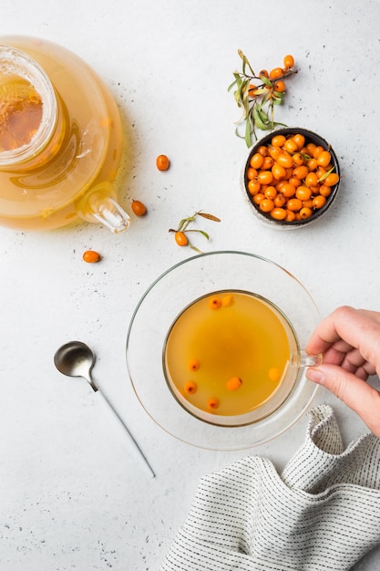 Tea with sea buckthorn on white stone background. top view