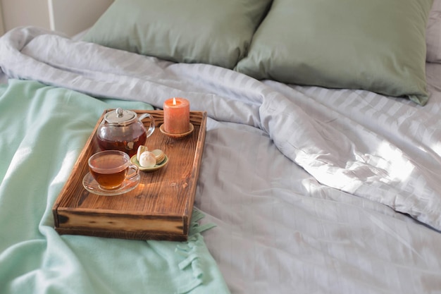 Tea on wooden tray on bed at home