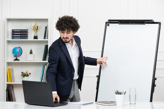 Teacher brunette instructor with computer in suit and whiteboard in classroom typing on keyboard